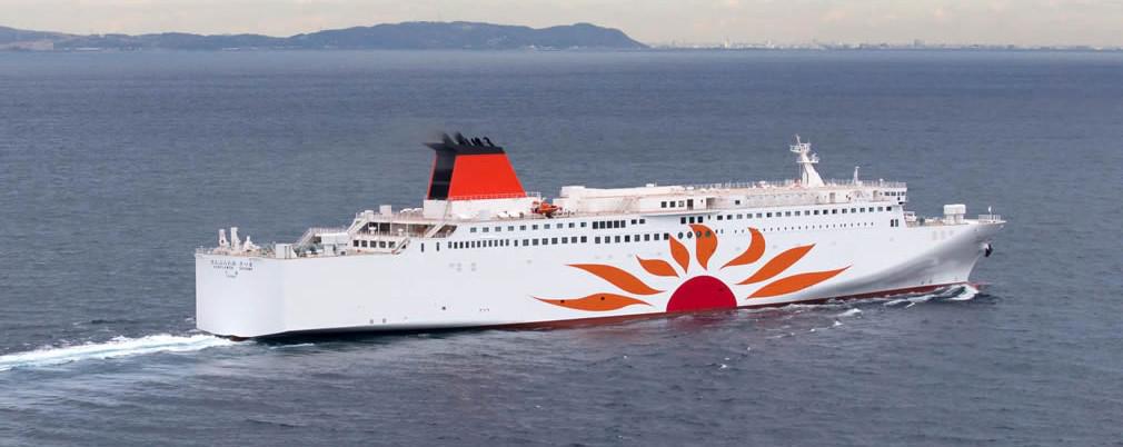 Tranquil ferry ride with a view of distant mountains and a setting sun over Japanese waters